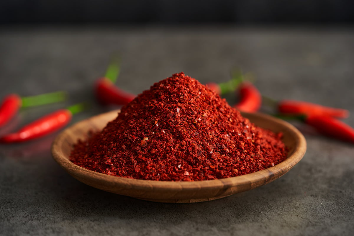 red chili pepper flake or ground powder coarse in wood bowl on gray stone food background. red chili pepper flake or ground powder coarse food. red chili pepper flake or ground powder coarse